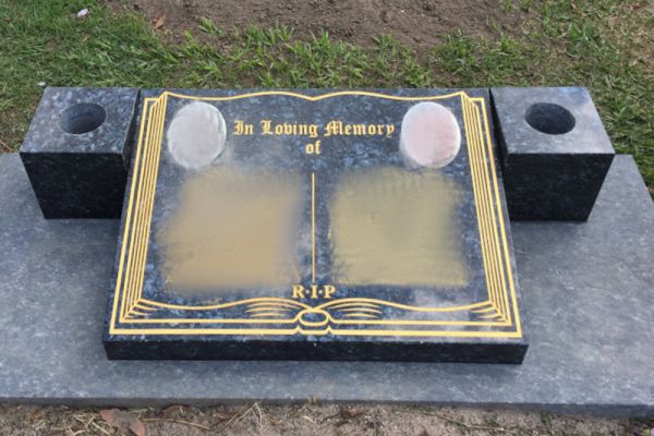 Gravestone with dual vases, gold inscription and portrait photos.