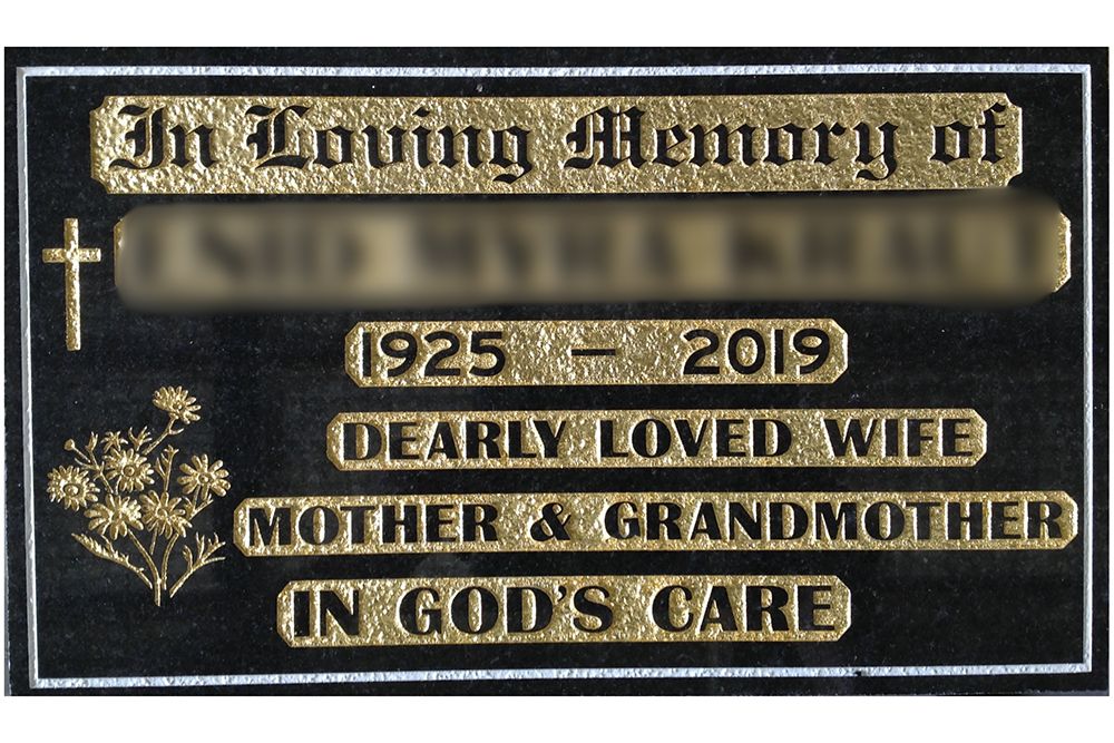 An example of memorial plaque wording with a gold incised inscription and religious and floral embellishments.