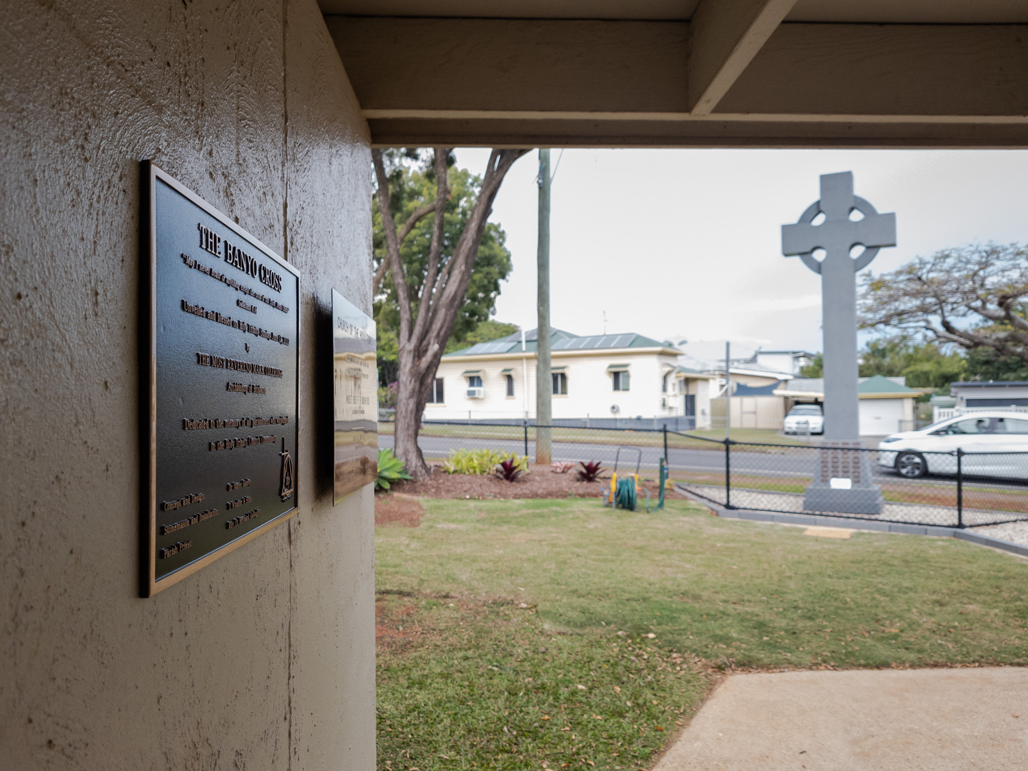 Commemorative bronze and brass plaques with the finished granite cross in the background.