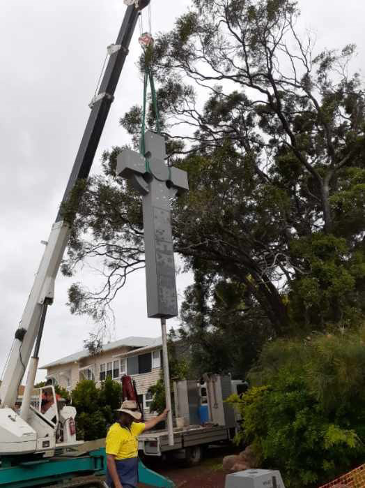 Lifting the cross into place with a crane to begin to carefully place it onto its foundation.